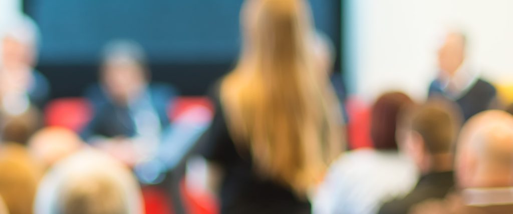 blurry image of speaker addressing board